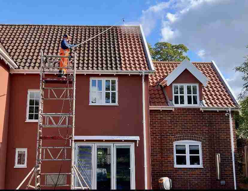 Roof cleaning in progress on a red tiled large house roof.